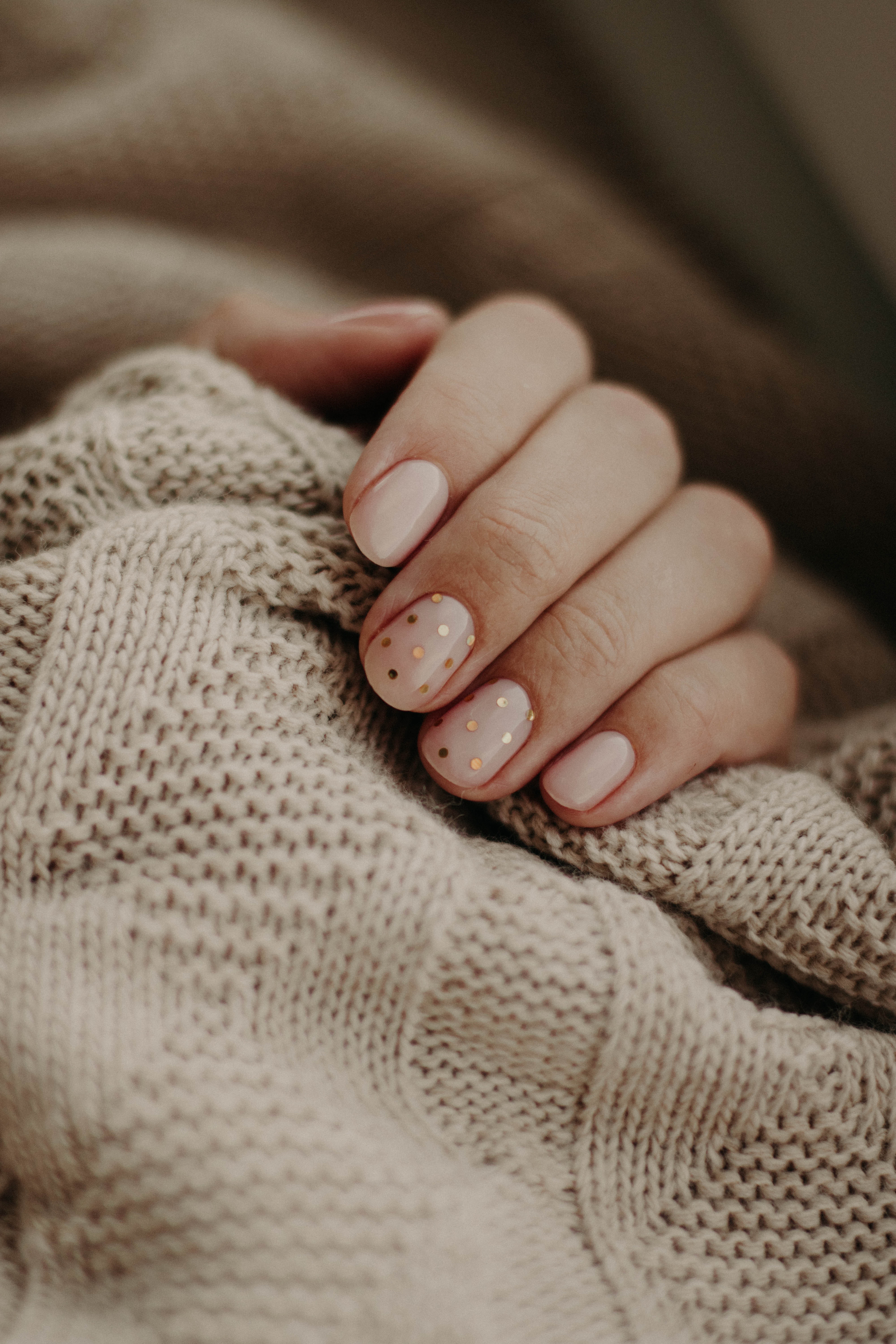 Photo of a hand on a sweater by Kristina Paukshtite.  Image shows four fingers curving around the edge of a textured sweater in a natural color. Image available at: https://www.pexels.com/photo/photo-of-person-s-hand-3557600/